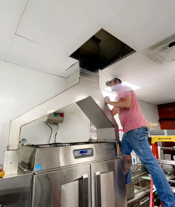Payton, Titan Mechanical's Co-Owner installing a custom dishwasher ventilation system for Pizza Ranch!
